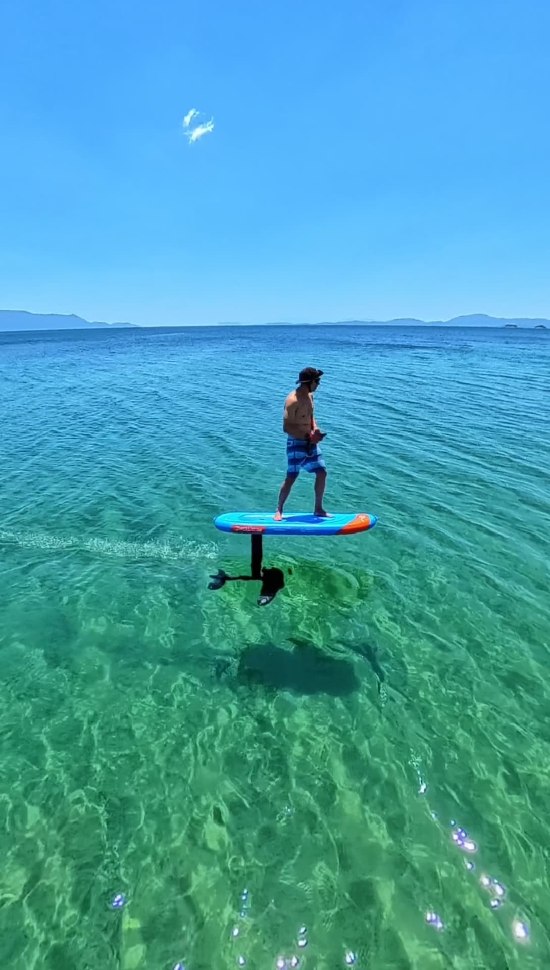 E-foil rider flying above crystal clear turquoise shallows in Greece