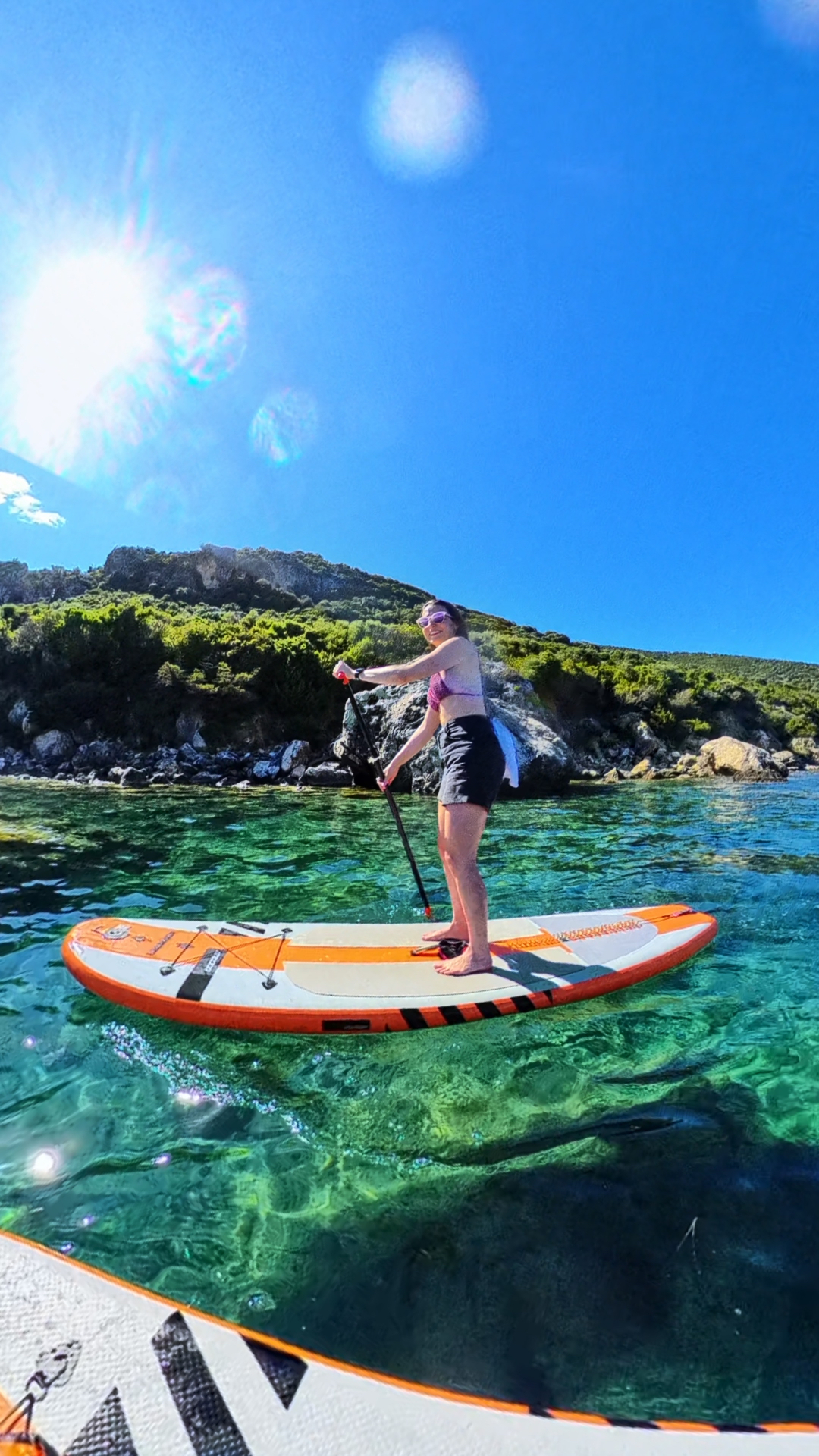 Paddleboarder smiling under bright Greek sunshine