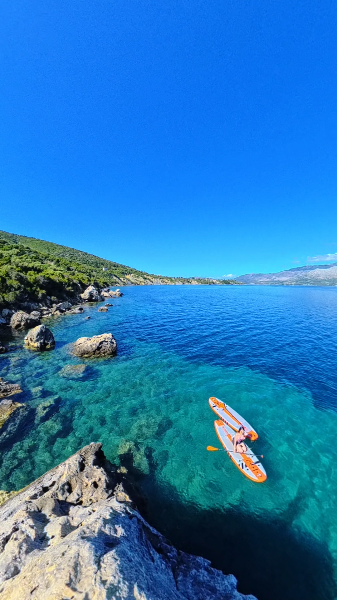 Aerial view of a paddleboarder on crystal clear Ionian water